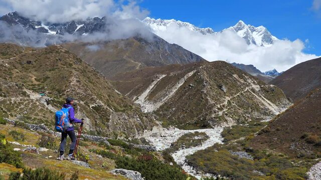 Active hiker hiking, enjoying the Mount Everest view, Nepal mountain range. Static zoom shot 