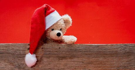 Obraz na płótnie Canvas Teddy bear with santa hat, red color background