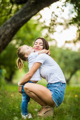 Fototapeta premium Young mother and daughter hugging in love playing in the park