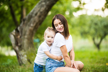 Fototapeta premium Young mother and daughter hugging in love playing in the park