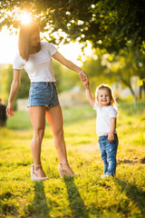 Fototapeta premium Happy mother dancing with her daughter in park on sunset