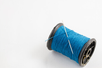 spool of blue thread and a needle