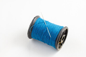 spool of blue thread and a needle