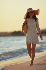 relaxed elegant woman on ocean coast at sunset walking