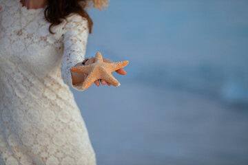 Closeup on woman on seashore at sunset showing starfish