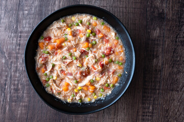 Puerto Rican Chicken Rice Soup in a black stoneware bowl on a dark wood table