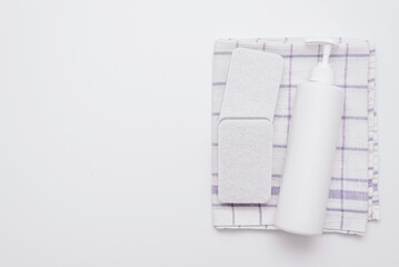 White bottle of liquid soap or detergent, sponges and towel on white flat lay background with copy space.