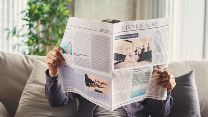 Senior man reading newspaper at home - Powered by Adobe