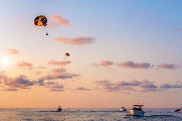 People flying with a yellow parachute by speed boat on sea