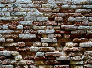 Selective focus. Collapsing natural wall of an old house with brick masonry. Vintage stone background. Italy. Venice.