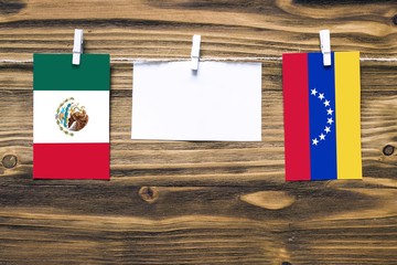Hanging flags of Mexico and Venezuela attached to rope with clothes pins with copy space on white...