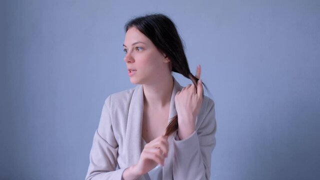 Beauty blogger talking about hairs care and problems recording video looking at camera. Young woman freelancer bloffer vlogger working. Portrait of girl on grey background.