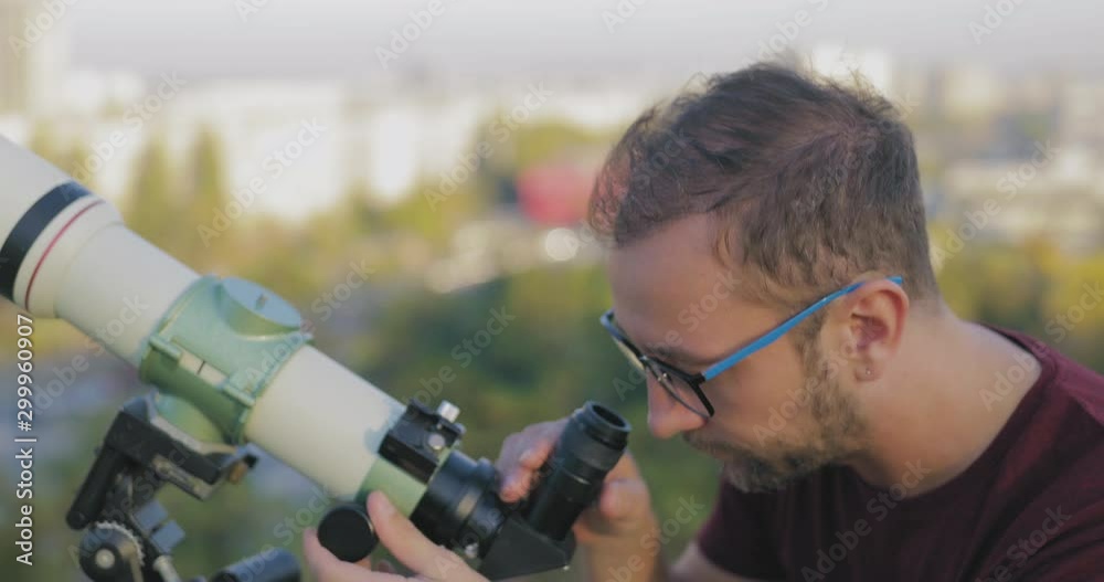 Canvas Prints astronomer with a telescope watching at the stars and moon with blurred city background.