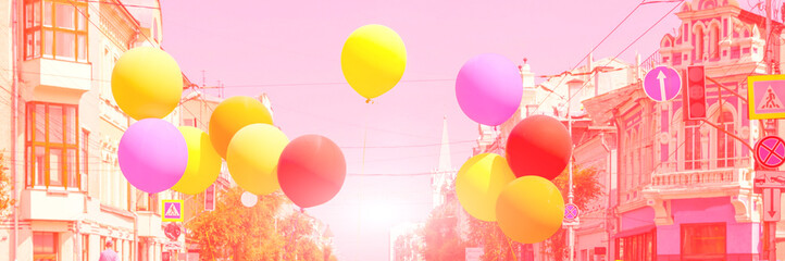 Multi-colored balloons on a background of urban buildings.