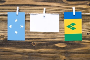 Hanging flags of Micronesia and Saint Vincent And The Grenadines attached to rope with clothes pins...