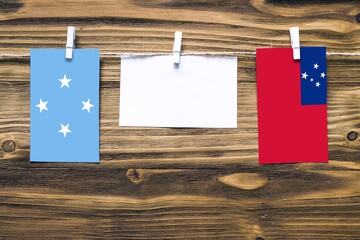 Hanging flags of Micronesia and Samoa attached to rope with clothes pins with copy space on white note paper on wooden background.Diplomatic relations between countries.