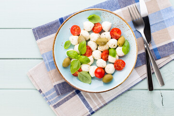 Delicious caprese salad with ripe cherry tomatoes and mini mozzarella cheese balls with fresh basil leaves.