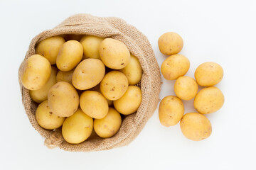 Sack of fresh raw potatoes on wooden background, top view