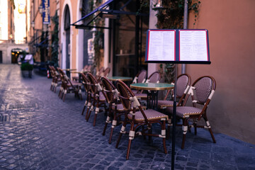 Cozy italian restaurants exterior, famous cafes on the streets of ancient roman empire. Wooden tables and chairs of restaurant, special menu and tourists attractions. Italian local colouring