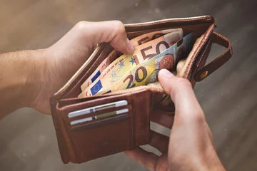 Fotobehang Hands opening a leather wallet with Euro banknotes inside © photoschmidt