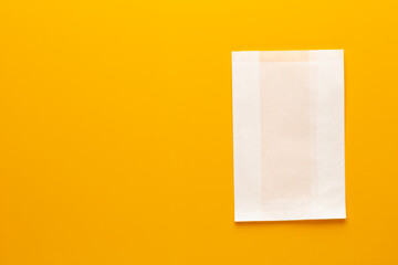 White paper bag on yellow background.
