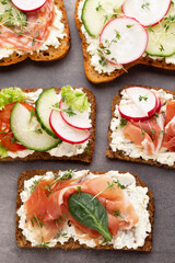 Sandwich with cereals bread and salami on dark marble background.