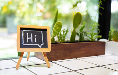 Word Hi sign on the blackboard on the wooden table, the background is a cactus in restaurants,...