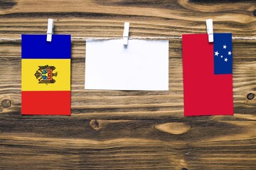 Hanging flags of Moldova and Samoa attached to rope with clothes pins with copy space on white note...