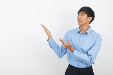 Young asian business man with blue shirt pointing to the side with hands to present a product or an idea while looking forward smiling isolated on white background.