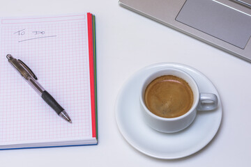 Mesa blanca con ordenador portátil, taza de café y libreta