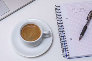 mesa blanca con taza de café, ordenador portátil y libreta