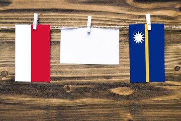 Hanging flags of Monaco and Nauru attached to rope with clothes pins with copy space on white note paper on wooden background.Diplomatic relations between countries.