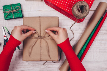 Gift wrapping. Woman packs holiday gifts at home on wooden table.