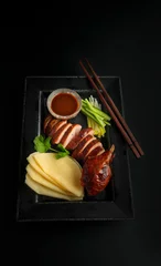 Wall murals Beijing Sliced peking duck with pancakes on a plate on a black background