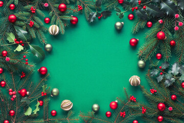Creative Christmas flat lay on green paper with copy-space. Frame made of fir and holly twigs,...