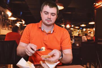 Young man wearing orange color tshirt eating at restaurant