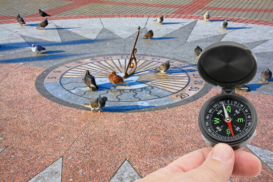 Compass In Hand On Background Sundial