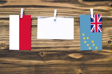 Hanging flags of Monaco and Tuvalu attached to rope with clothes pins with copy space on white note paper on wooden background.Diplomatic relations between countries.