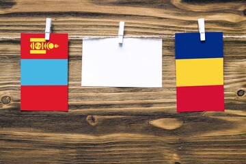 Hanging flags of Mongolia and Romania attached to rope with clothes pins with copy space on white...