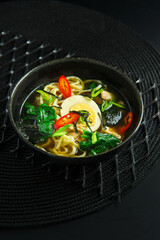 Traditional vietnamese soup with vegetables and mushrooms on black background