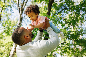 Father playfully lifting little boy in the air
