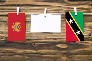 Hanging flags of Montenegro and Saint Kitts And Nevis attached to rope with clothes pins with copy space on white note paper on wooden background.Diplomatic relations between countries.