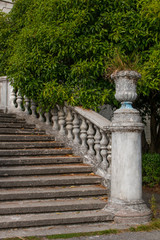 Old stone balustrade of railing background of green trees. Classic design and architecture. A picturesque landscape.