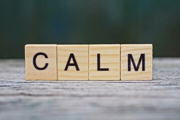 word calm from wooden letters on a gray table on a green background