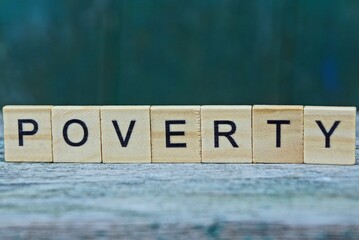 the word poverty from wooden letters on a gray table on a green background