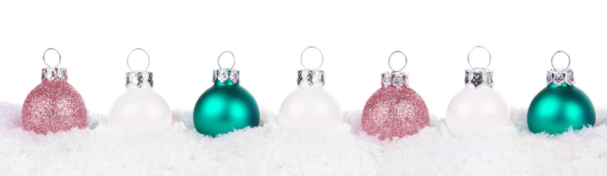 Christmas border of dusty rose, white and teal ornaments resting in snow isolated a white background