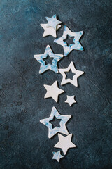 Christmas decoration ceramic stars white and blue glazed, different size, over blue texture background. Christmas and New year greeting card. Flat lay, space.