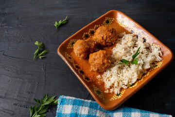 Mexican meatballs with red sauce and rice on dark background