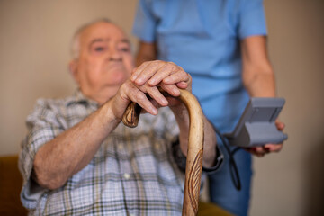 Nurse is measuring blood pressure of an elderly man