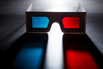 Movie at cinema concept. 3D glasses with red and blue lenses with soft colored shadow on dark...